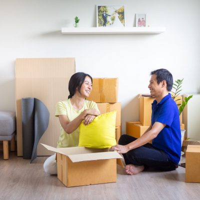 Young smiling couple bonding sitting on floor in new home with boxes on moving day. Happy homeowners or renters just moved into modern house. family relocation and delivery service concept.